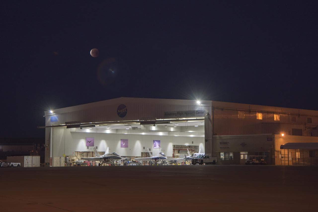 Image is NASA Armstrong Flight Research Center's aircraft hangar that houses the jets and other aircraft with the eclipsed moon overhead during Jan. 31 Super Blue Blood Moon.