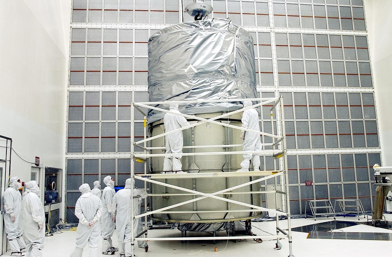KENNEDY SPACE CENTER, FLA.  -  Working from a stand, technicians fasten the upper portion of the canister to the middle panels around the Space Infrared Telescope Facility (SIRTF).  The spacecraft will be transported to Launch Complex 17-B for mating with its launch vehicle, the Delta II rocket.   SIRTF consists of three cryogenically cooled science instruments and an 0.85-meter telescope, and is one of NASA's largest infrared telescopes to be launched.  SIRTF will obtain images and spectra by detecting the infrared energy, or heat, radiated by objects in space. Most of this infrared radiation is blocked by the Earth's atmosphere and cannot be observed from the ground.