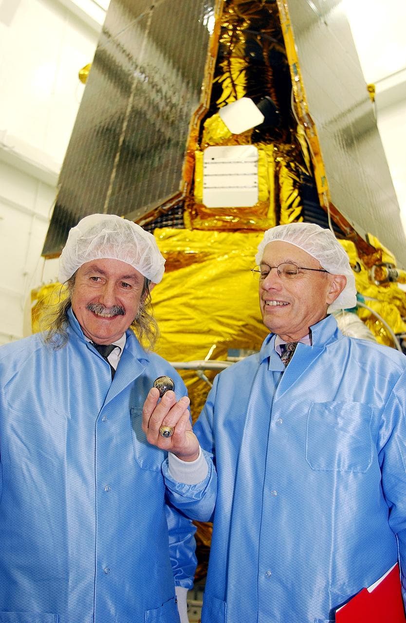 VANDENBERG AFB, CALIF. -  In the NASA spacecraft processing facility on North Vandenberg Air Force Base,  Dr. Francis Everitt, principal investigator, and Brad Parkinson, co-principal investigator, both from Stanford University, hold one of the small gyroscopes used in the Gravity Probe B spacecraft.  The GP-B towers behind them.  The Gravity Probe B mission is a relativity experiment developed by NASA’s Marshall Space Flight Center, Stanford University and Lockheed Martin.  The spacecraft will test two extraordinary predictions of Albert Einstein’s general theory of relativity that he advanced in 1916: the geodetic effect (how space and time are warped by the presence of the Earth) and frame dragging (how Earth’s rotation drags space and time around with it).  Gravity Probe B consists of four sophisticated gyroscopes that will provide an almost perfect space-time reference system.  The mission will look in a precision manner for tiny changes in the direction of spin.