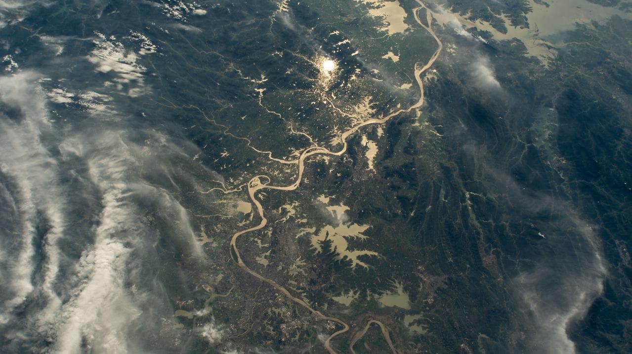The Yangtze River beams in the Sun's glint and surrounded by wildfires