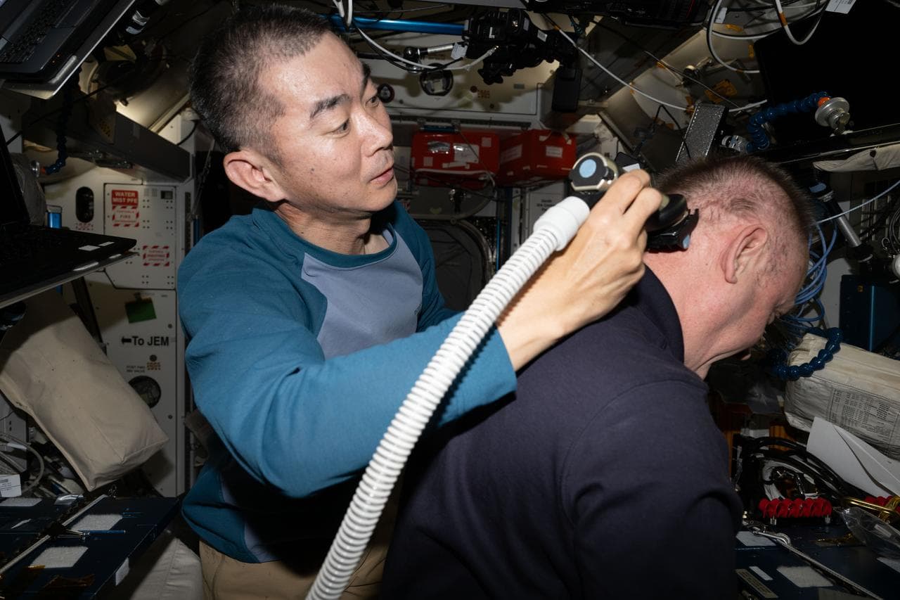 JAXA astronaut Kimiya Yui trims NASA astronaut Mike Fincke's hair aboard the International Space Station