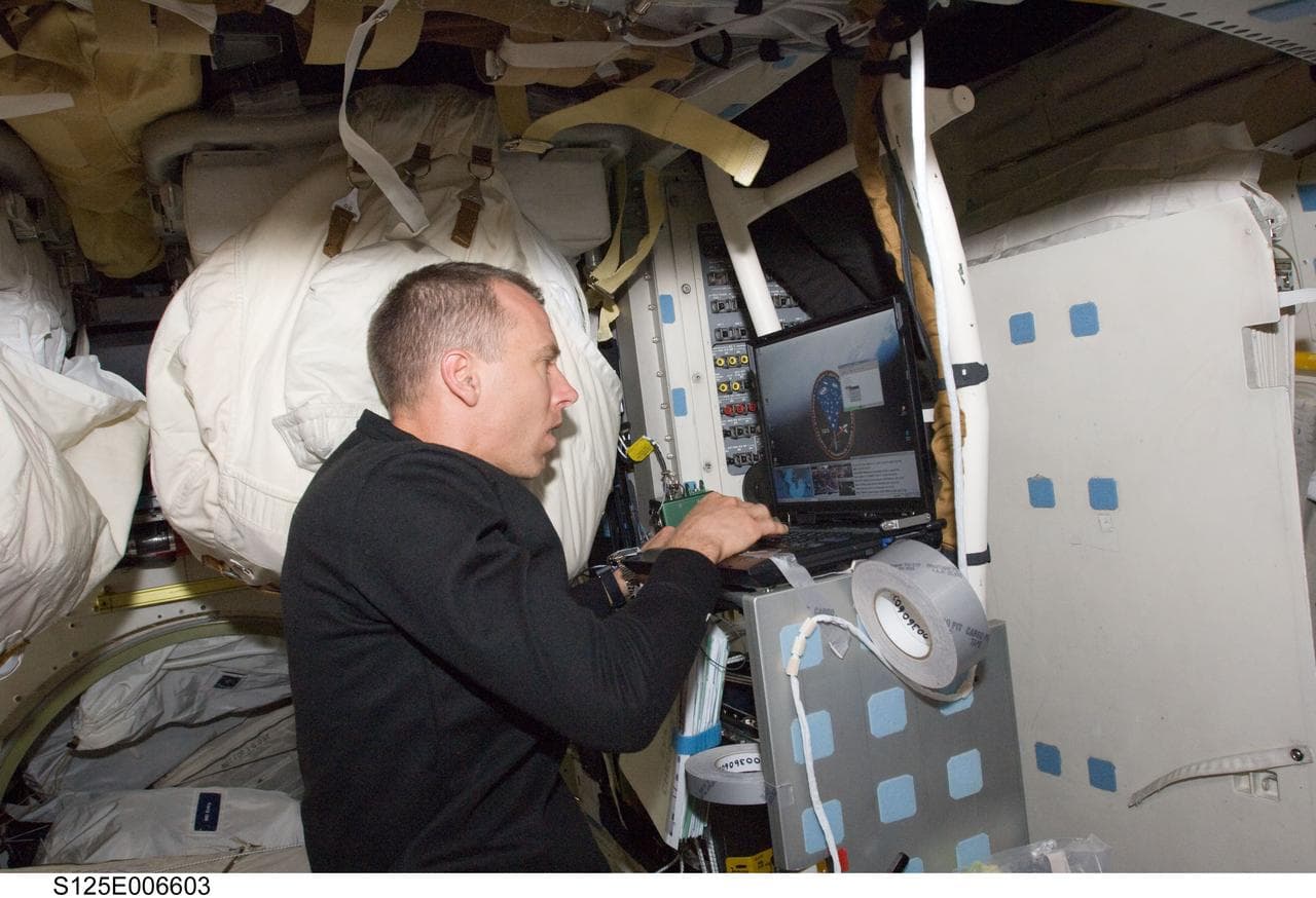 Feustel working on a Laptop on the Shuttle Atlantis Middeck