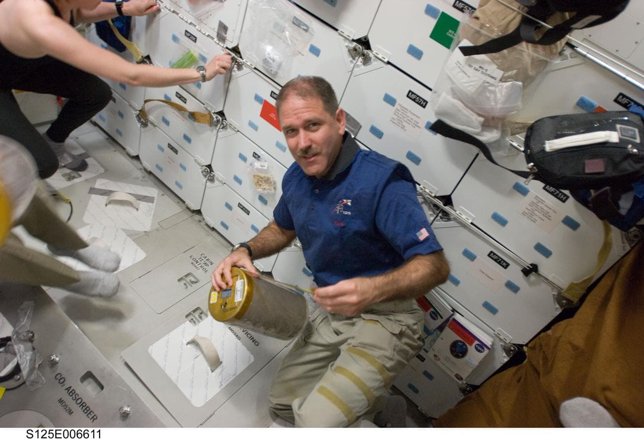 STS-125 Crew Members replace LiOH Cannisters on the Shuttle Atlantis Middeck