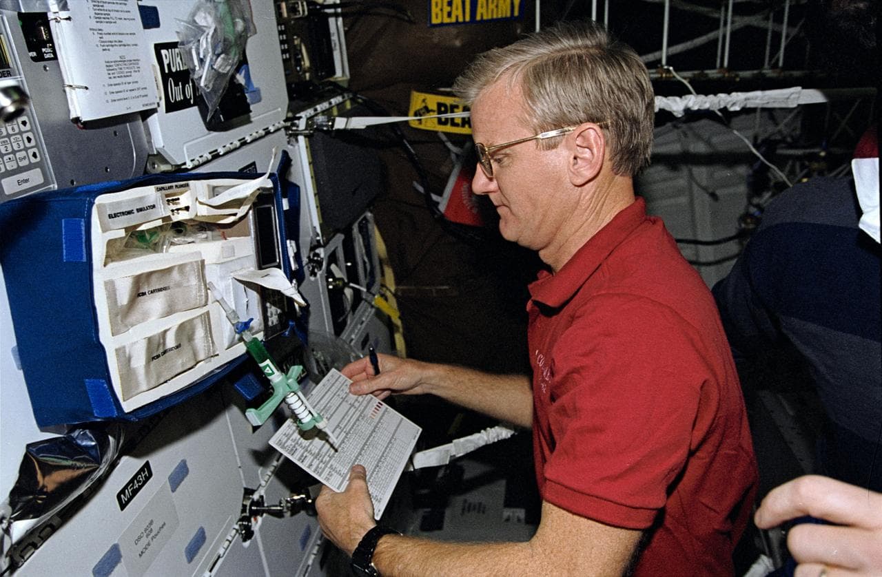 Astronaut John Casper checks equipment to support medical testing